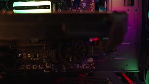 Inside a working gaming PC with rainbow lighting on the fans in the dark. Dolly slider, close up.