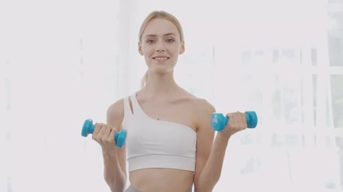 Beautiful young woman workout with lift up dumbbell for muscle while motivation.