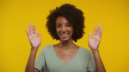 Woman Smiling and Waving on Yellow Background