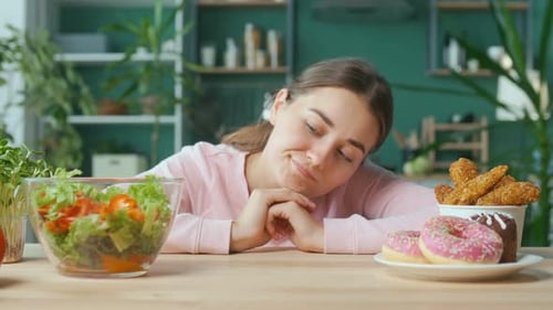 Una mujer en la cocina elige entre alimentos orgánicos saludables y rosquillas glaseadas
