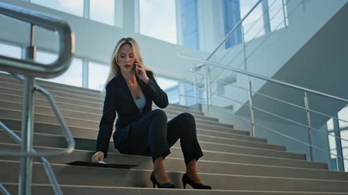 Worried Woman Sitting on Stairs Talking on Phone