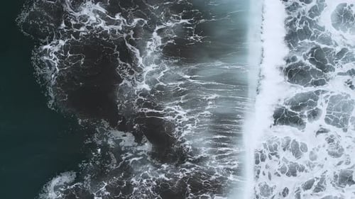 Aerial view of some powerful ocean waves crashing into the shore. Slow motion, 4k.