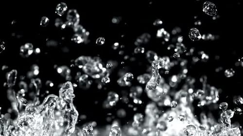 Wassertröpfchen steigen und fallen auf einem schwarzen Hintergrund, gefilmt mit einer Hochgeschwindigkeitskamera mit 1000 Bildern pro Sekunde