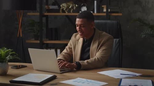 Black Male Entrepreneur Working on a Laptop in His Home Office A Man Businessman Sits at a Table on