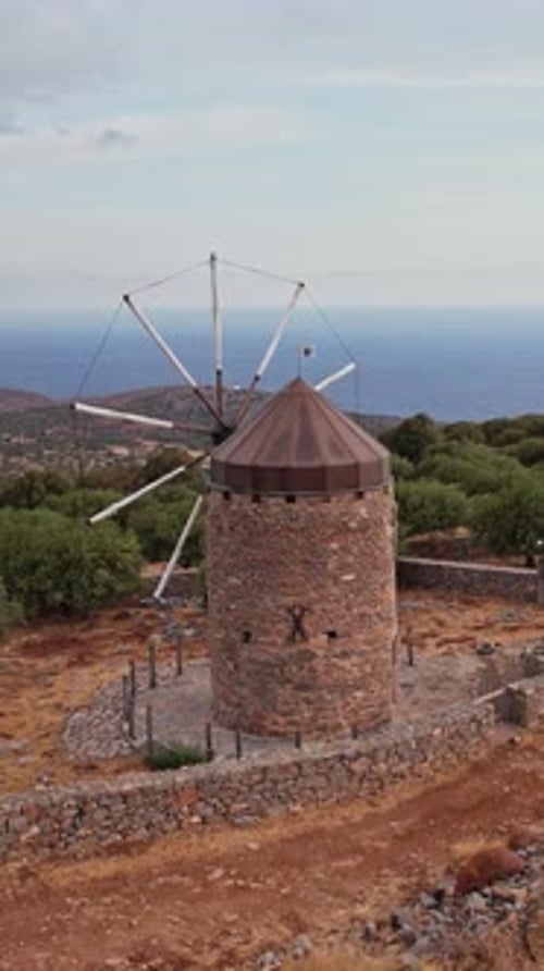 Ancient windmills overlooking the ocean on a Greek island at dusk