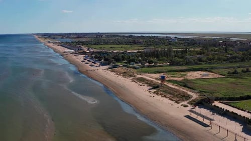Beautiful flight in summer over the beach. People are resting near the sea. Houses for tourists.