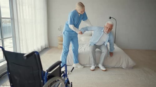 Caregiver Helping Senior Man Getting Out of Bed