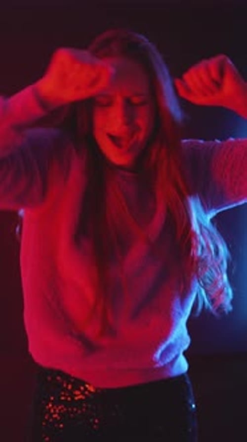 Enthusiastic Woman Dancing with Energy in Colorful Light