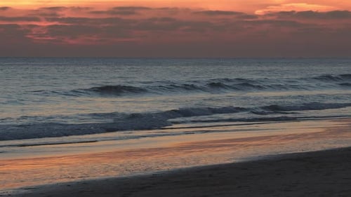 Waves approaching sandy coastline at dusk time in the Atlantic Ocean at Portugal coast.