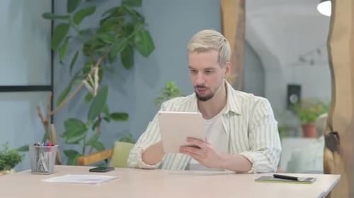 Man Gesturing Disgust While Using Tablet Indoors