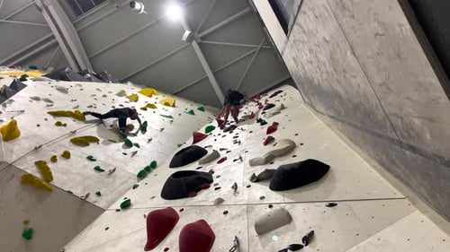 Des gens escaladent un mur impossible à l'intérieur d'un gymnase. Ralentissement Cinématographique