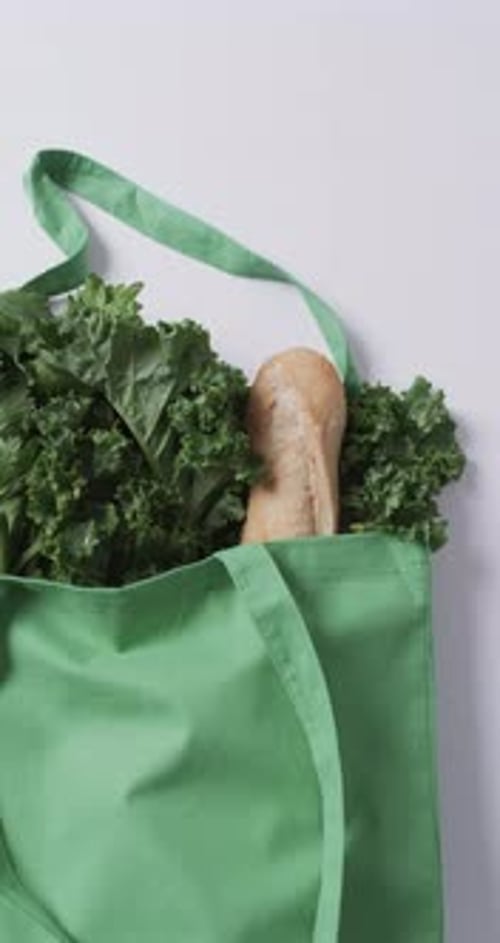 Vídeo vertical de bolsa de lona verde con perejil, col rizada y baguette, espacio para copiar sobre fondo blanco