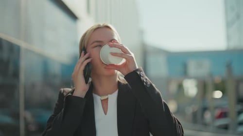 White Woman on Call Drinking Coffee Walking By Office Building Outdoors