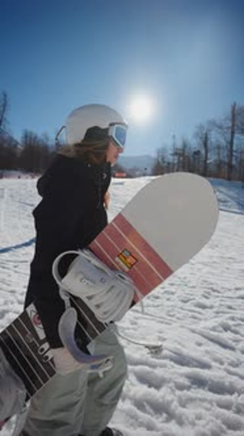 Woman with Snowboard Walking on Snowy Hillside
