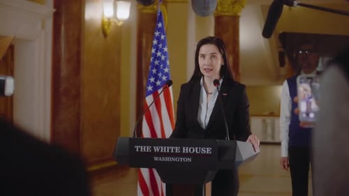 Woman Speaking at Press Conference with American Flag