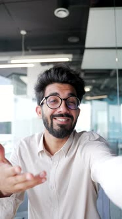 POV Webcam view. Vertical video. Smiling bearded man in glasses talking on a video call using