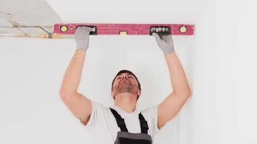 Man Measures Wall with Spirit Level