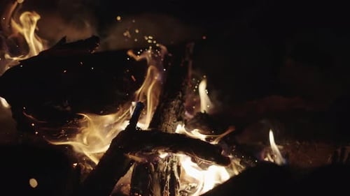 Slow Motion Shot Campfire poked by wooden stick. Logs are on fire, sparks fly. 4k,
