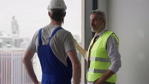 Engineer Contractor Working with Young Electrician on New Building