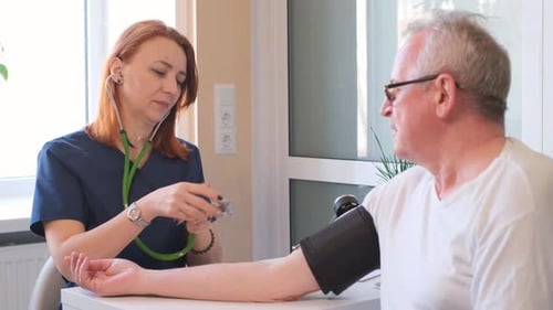 Female Cardiologist Measuring Blood Pressure of an Elderly Patient at Doctor's Office