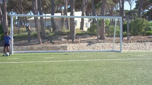 Auf dem Rasen nimmt der Stürmer den Ball entgegen, dribbelt und schießt im Training aufs Tor, Torwartstrebe
