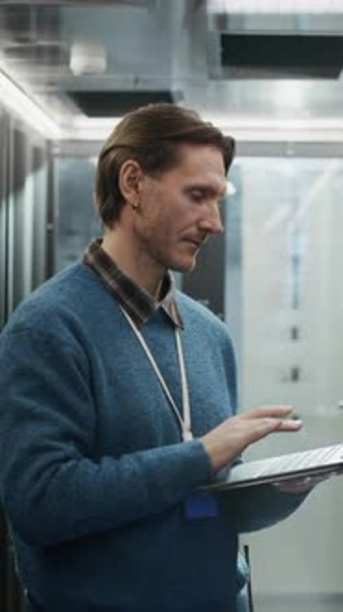 Vertikales Porträt eines Netzwerktechnikers, der Server mit Laptop überwacht