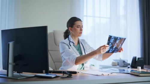 Woman Doctor Examines X-Ray in Office