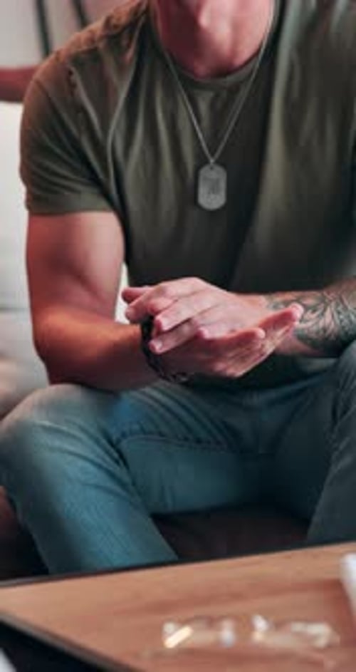 Tattooed Man Rubs Hands Together While Sitting Indoors