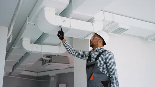 Indian Worker Install Ducted Pipe System for Ventilation and Air Conditioning in Office