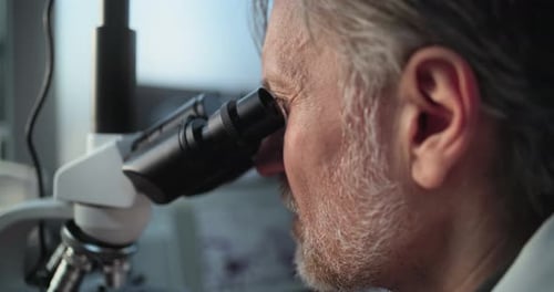 Imagem aproximada de um microbiologista maduro analisando amostras fósseis sob microscópio