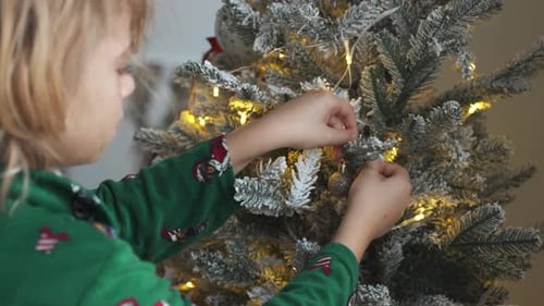 Girl Decorates Christmas Tree with Ornament at Home
