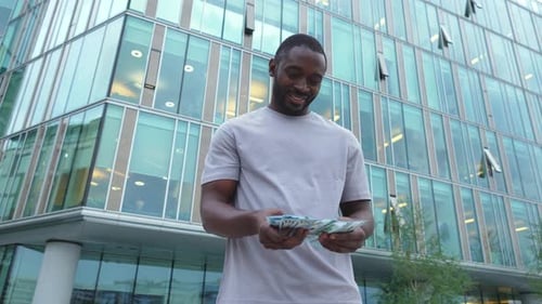 African American Man Holding Money Dollar Bills on Urban Street in City Businessman Guy Counting