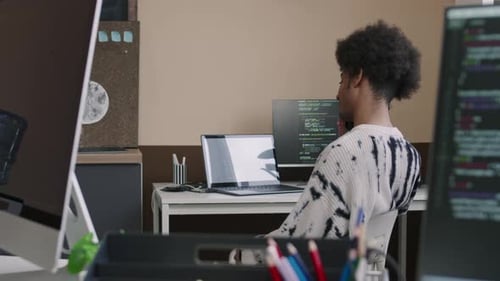 Biracial Male Programmer Spinning in Office Chair while Talking on Smartphone