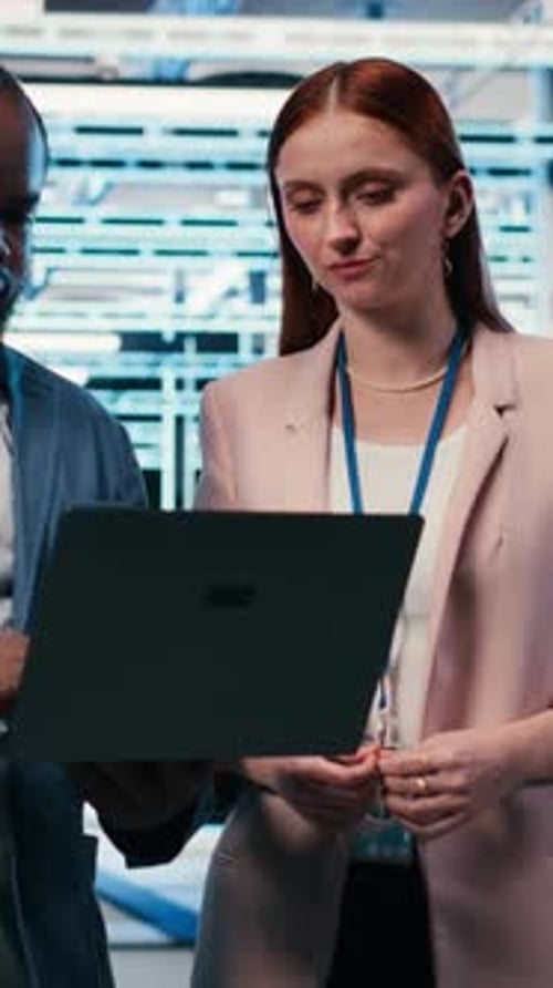 Vertical Video Engineering Team in Server Hub Working Together with Laptop to Do Maintenance