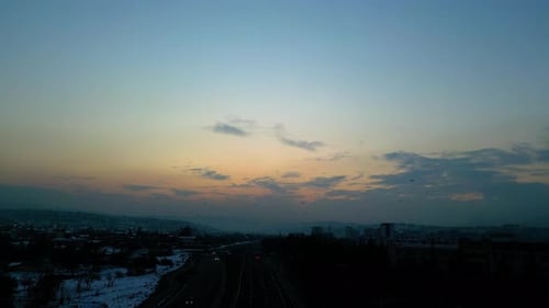 At sunset, a drone flying with crows over the road