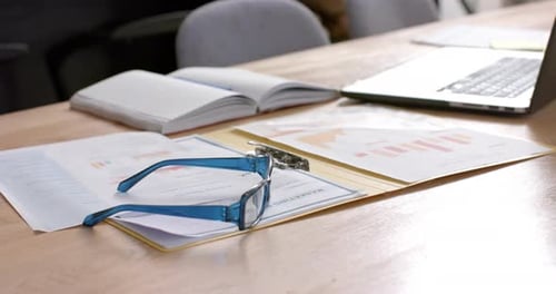 Documents and laptop on table at home, slow motion