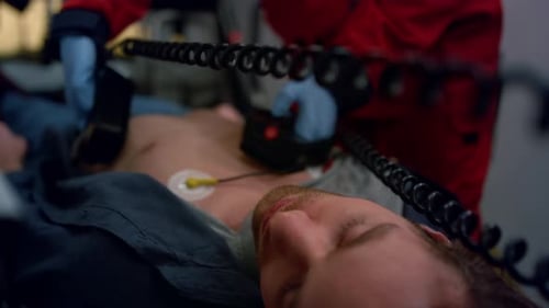 Emergency care doctor rescuing patient with external defibrillator in ambulance