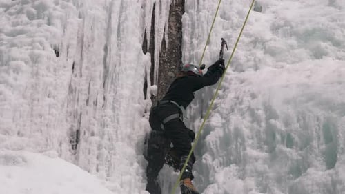 Eine Eiskletterin stellt sich der Herausforderung einer senkrechten gefrorenen Eiswand