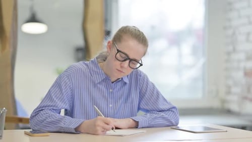 Young Woman Writing at Desk in Modern Office