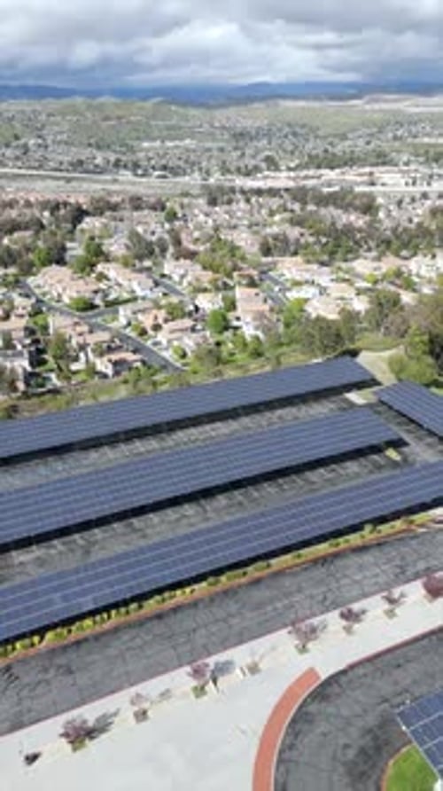 Solar panels generate clean, sustainable energy for a suburban community - vertical drone panorama
