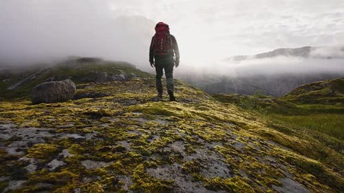 Explorador masculino difícil de escalar nas montanhas enevoadas
