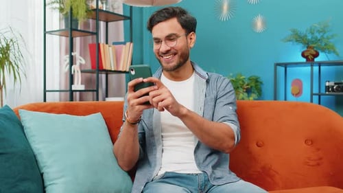 Young Adult Using Smartphone on a Couch Indoors