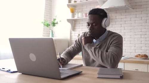 Young Man Works on Laptop at Kitchen Table