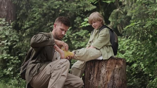 Dad Bandaging Son's Foot in Forest