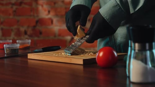 A Chef Grates Cheese Wearing Black Gloves in the Kitchen