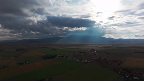 Drone : Vue aérienne de la lumière du soleil traversant les nuages dans un champ agricole