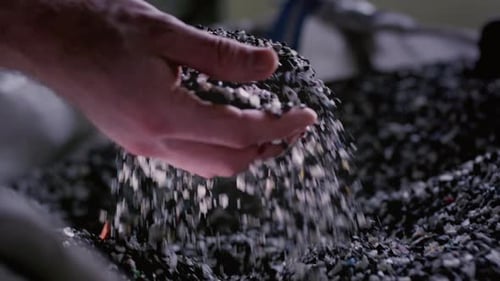 Hand Touches the Granules of Crumb Microplastics Polymer Granules are Poured From the Palm