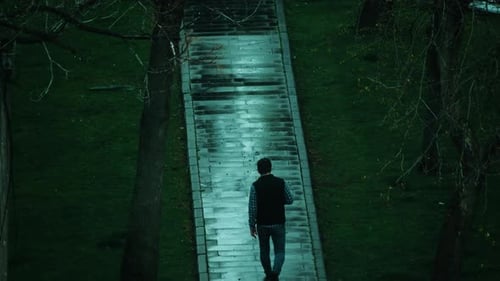 Young man walking through the park in rainy weather