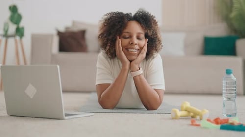 Woman Lying on Exercise Mat Looks at Camera