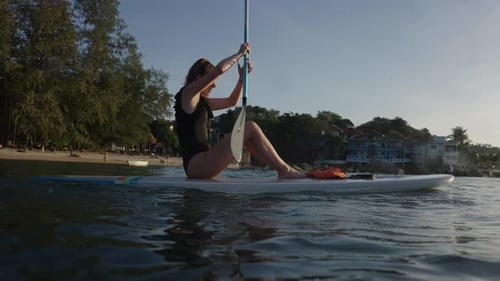 Woman Paddleboarding at Sunrise on Tropical Beach